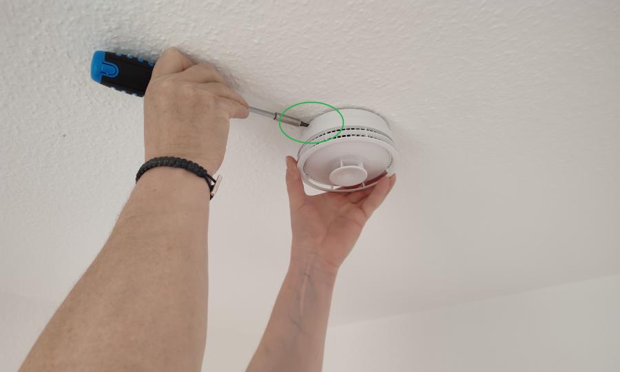 Person montiert einen Rauchmelder an der Decke